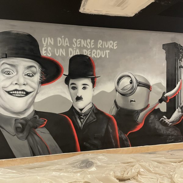 Mural de cine realizado por grafiteros profesionales con retratos realistas de Joker, Charles Chaplin y un Minion en blanco y negro con detalles en rojo.